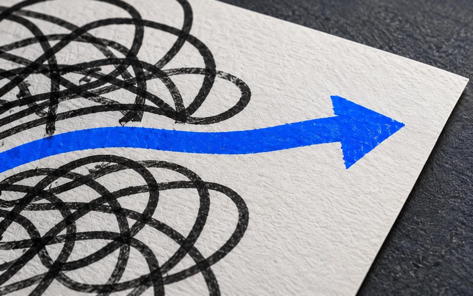 A blue arrow emerging from tangled charcoal lines on textured paper