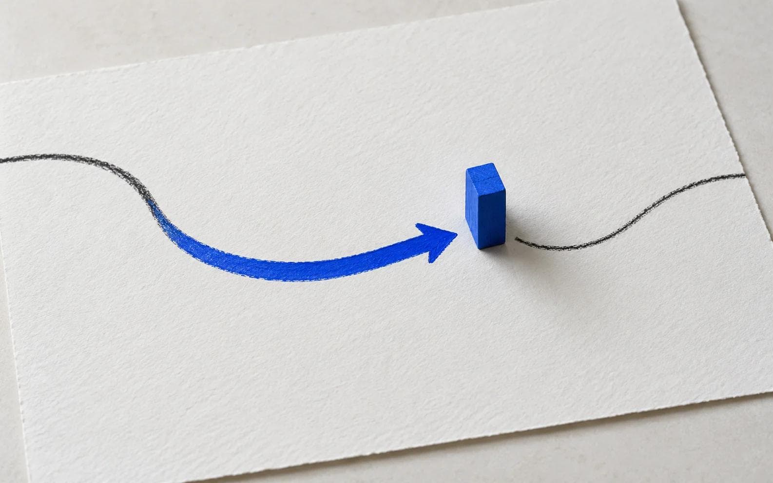 A hand marking a review point beside a blue arrow on paper
